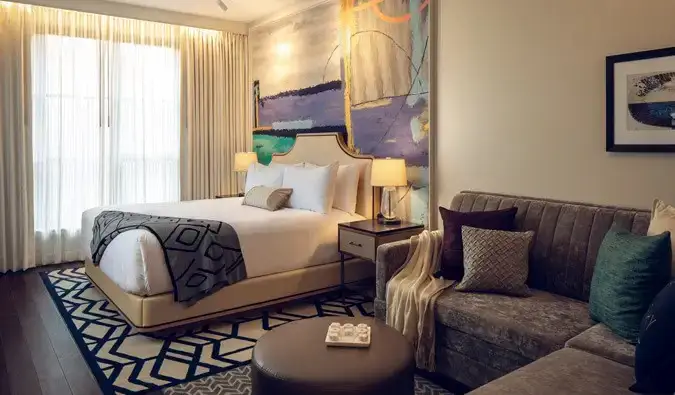 Habitació de luxe amb llit extragran a l'hotel Sophy Hyde Park de Chicago, decorada amb un estil contemporani amb un llit gran i un sofà seccional gris