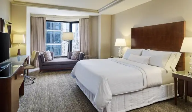 Malutong na puting king bed sa isang simple ngunit modernong idinisenyong kuwartong may tanawin ng bintana sa Westin Chicago River North Hotel