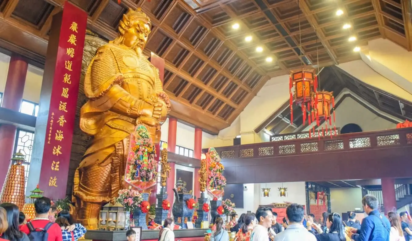 Die große goldene Statue des Kommandanten Che Kung, davor tummeln sich Menschen im Che Kung Miu Tempel in Hongkong