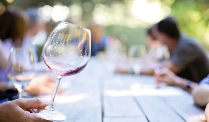 Weintrinken mit Freunden an einem Picknicktisch in Neuseeland