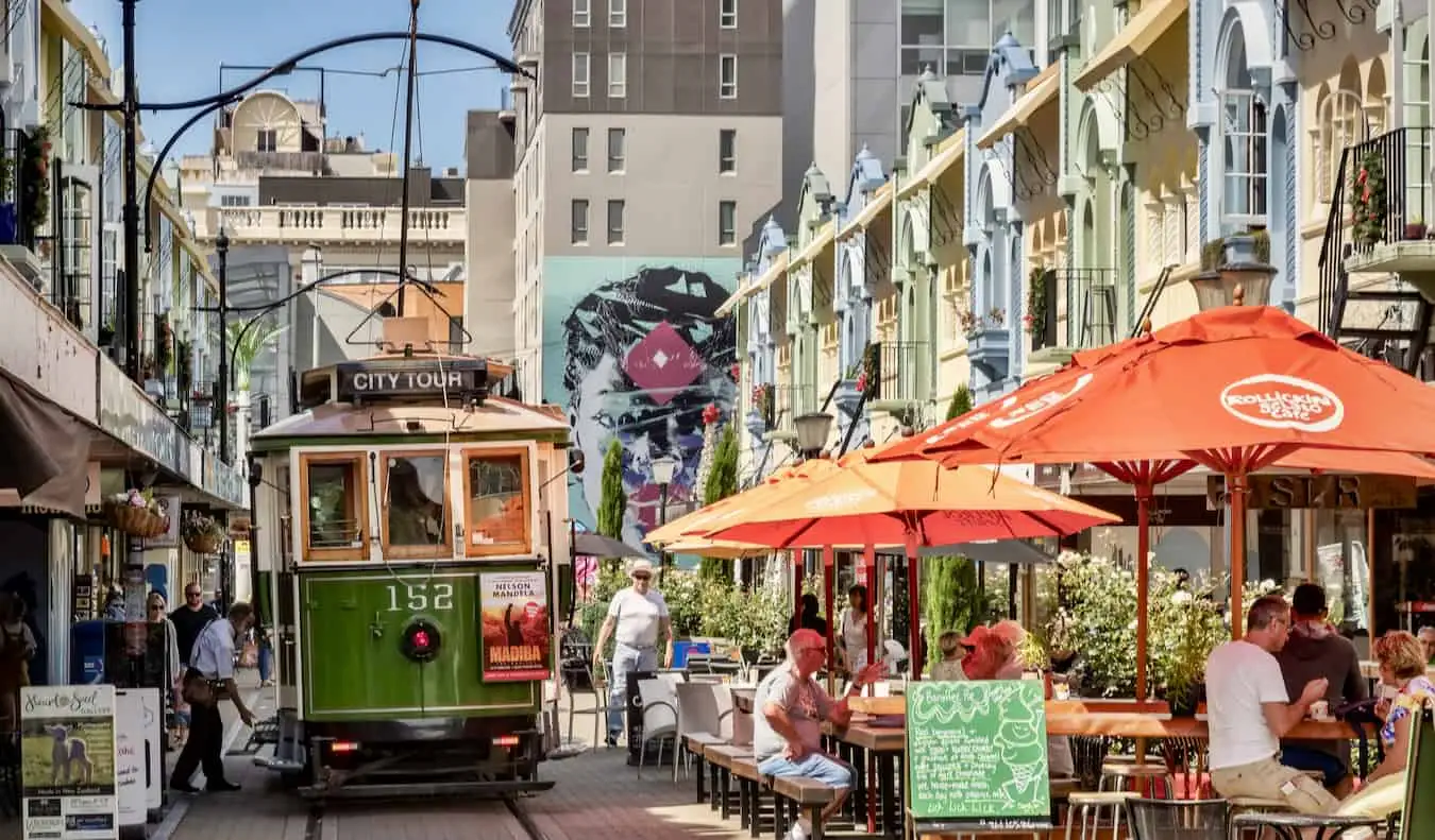 En historisk trikk cruiser ned en smal gate i solfylte Christchurch, New Zealand