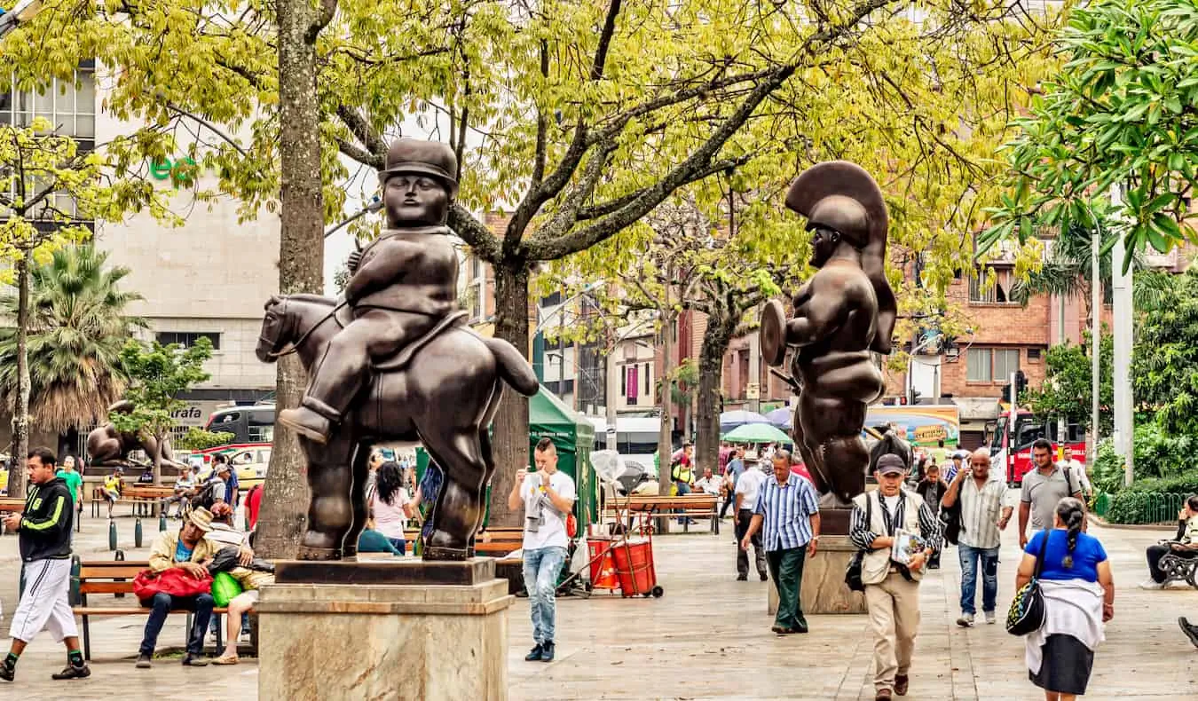 Botero sochy a ľudia, ktorí sa prechádzajú ulicami Medellínu v Kolumbii