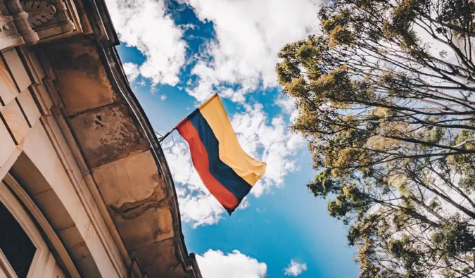 De vlag van Colombia wappert in de breedte terwijl hij aan een gebouw hangt