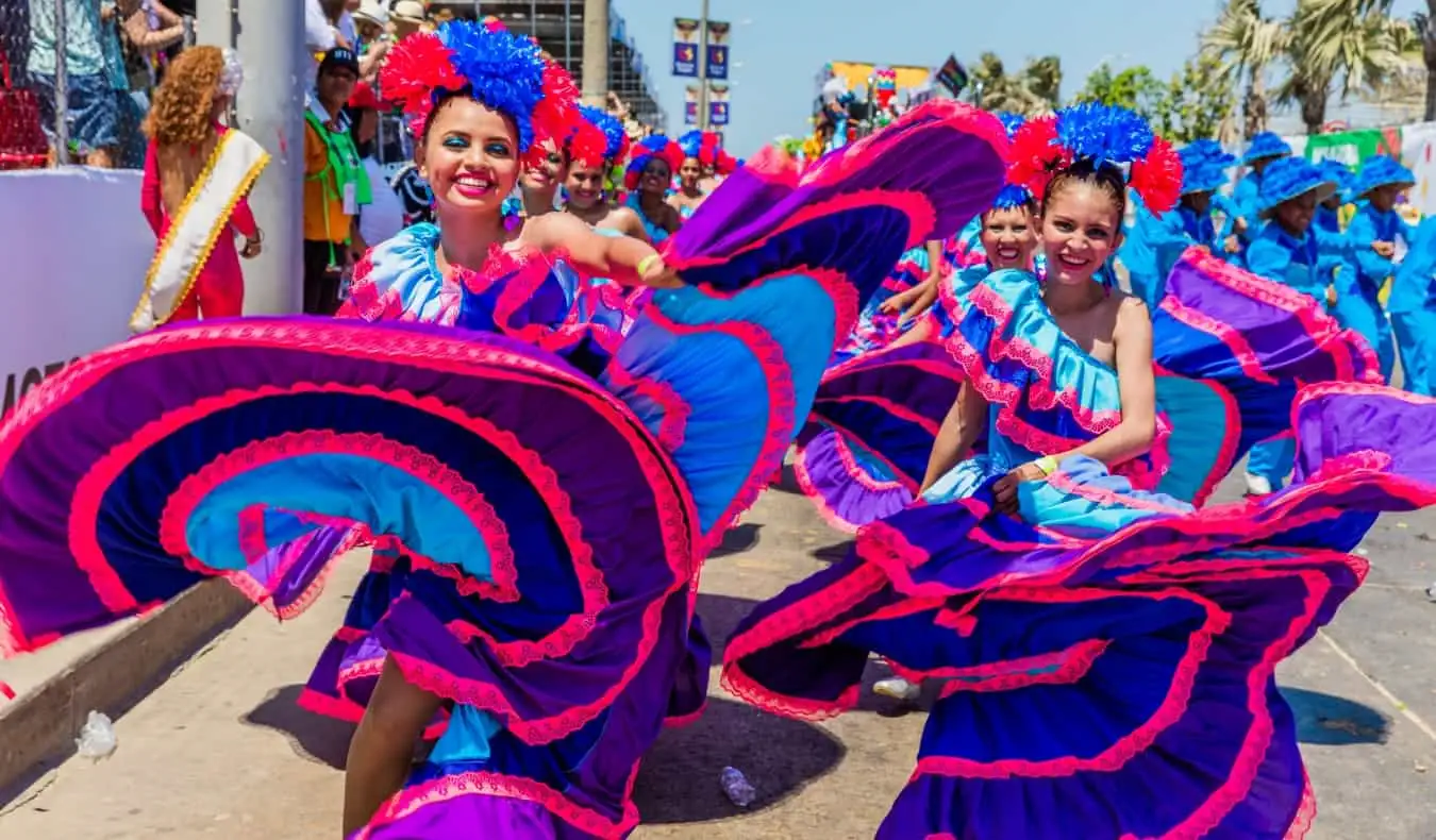 Kolombiya'nın Barranquilla kentindeki Karnaval sırasında parlak pembe ve mor elbiseli kadınlar dönüyor