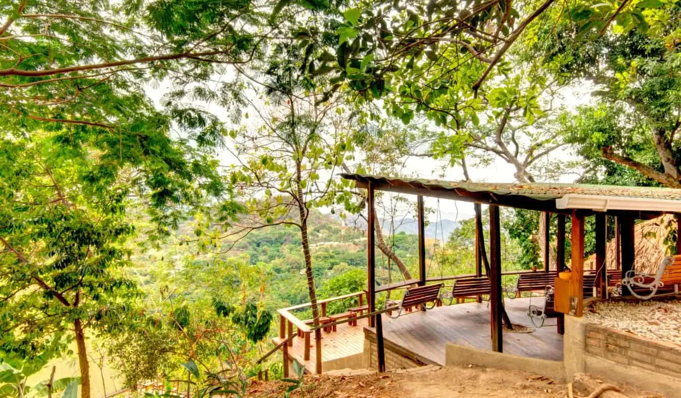 Tempat perlindungan berbumbung dengan bangku di hutan rimbun di Minca, Colombia