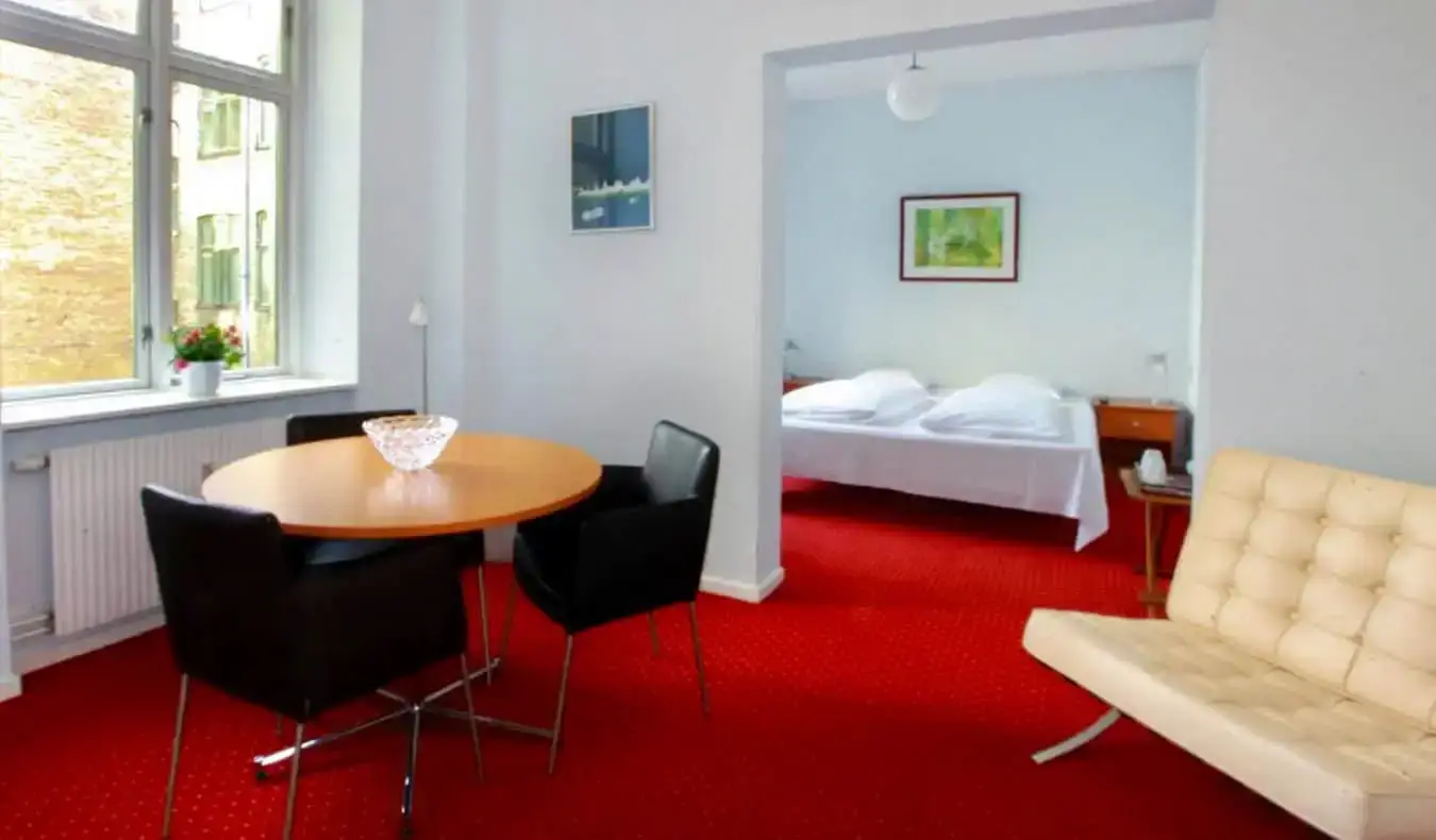 Um quarto de hotel arejado e espaçoso com tapete vermelho brilhante no Hotel Nora em Copenhague, Dinamarca