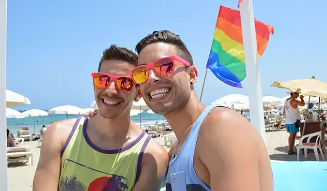 Auston e David de dois turistas malvados posando em uma praia no verão