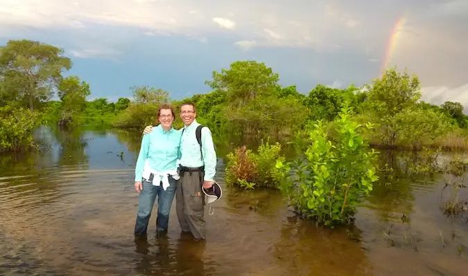 Un couple âgé voyageant dans un pays en développement avec un arc-en-ciel en arrière-plan