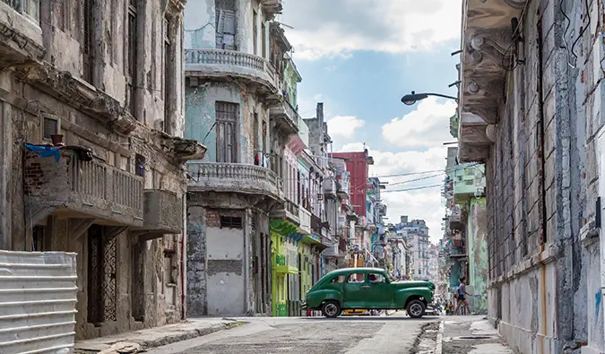 một chiếc ô tô màu xanh lá cây chạy ngang qua trên đường phố ở Havana