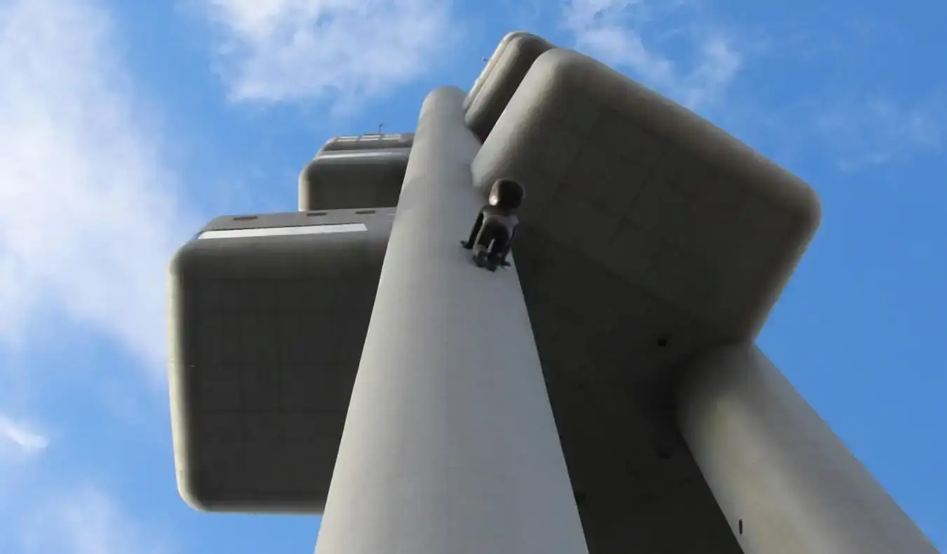 Opkijken naar een pilaar van de Zizkov TV-toren terwijl een grote zwarte sculptuurbaby erop klimt in Praag, Tsjechië