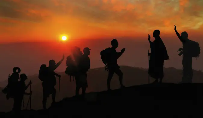 Un groupe de voyageurs escaladant une montagne pendant un coucher de soleil éclatant