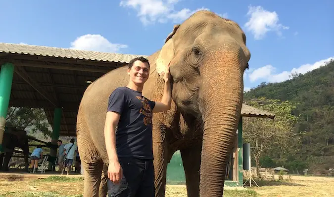 Nomadic Matt posiert mit einem Elefanten im Elephant Nature Park in Thailand