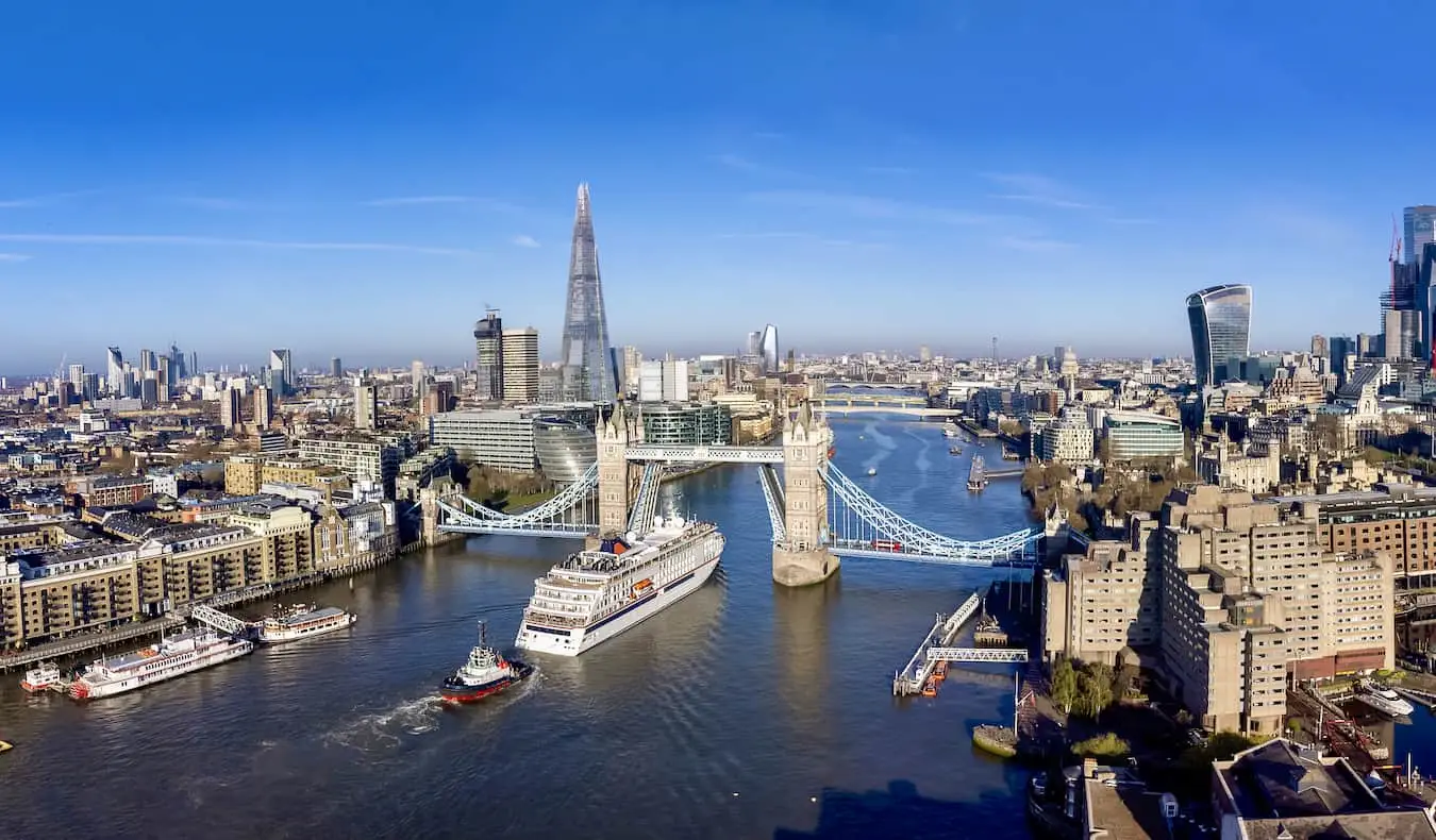 Den ikoniske Londons skyline over Themsen med båter som cruiser oppover elven