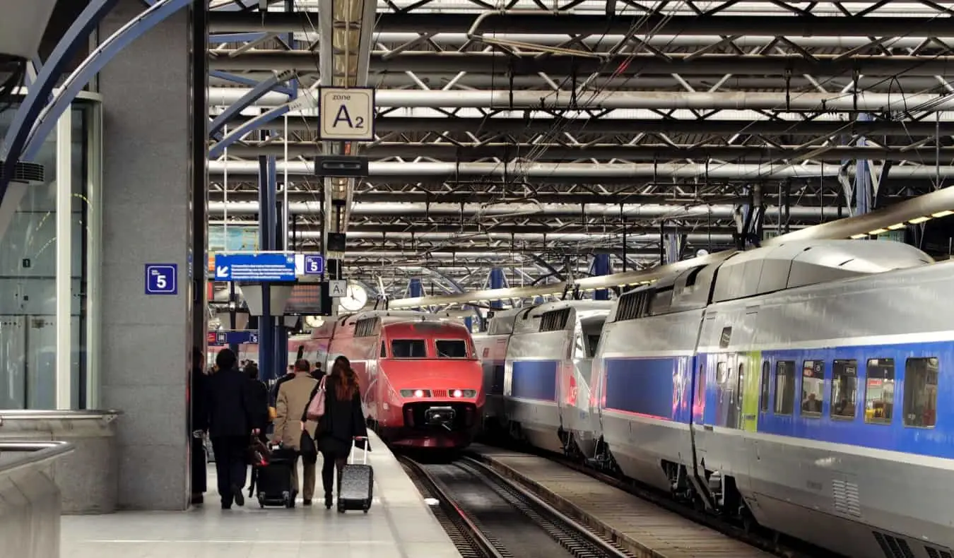 stazione ferroviaria con persone che trasportano bagagli accanto alle locomotive parcheggiate