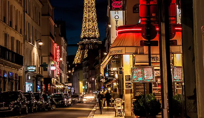 orang-orang berjalan di depan Menara Eiffel pada malam hari