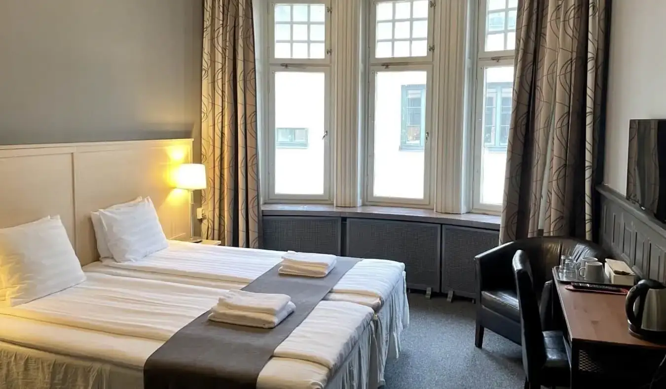 Kamar tamu berdekorasi simpel dengan tempat tidur ganda dan jendela besar di Unique Hotel di Stockholm, Swedia