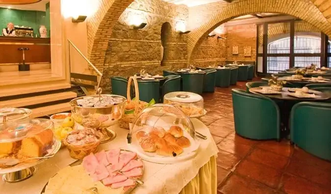 Prima colazione a buffet nella sala da pranzo con soffitti ad arco in pietra presso l'Hotel Laurentia a Roma, Italia