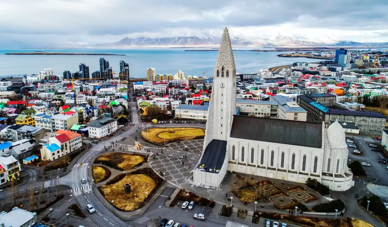 Şehrin alçak renkli binalarının üzerinde yükselen kendi plazasındaki bej İzlanda Kilisesi ile Reykjavik, İzlanda'nın havadan görünümü