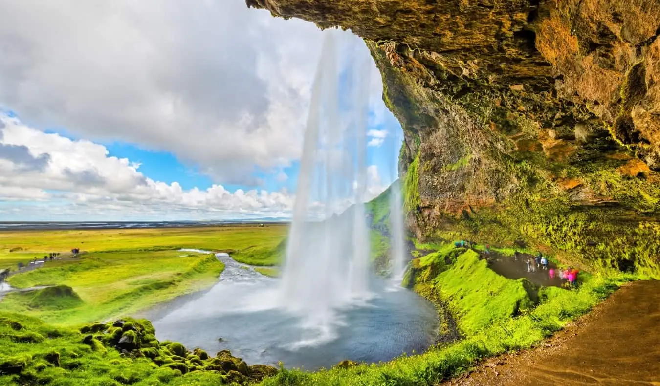 der riesige und beliebte Wasserfall Seljalandsfoss nahe der zerklüfteten Küste Islands