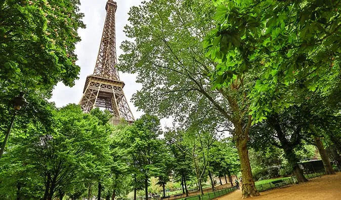 Menara Eiffel menyembul melalui tanaman hijau di lingkungan Champs de Mar, Paris