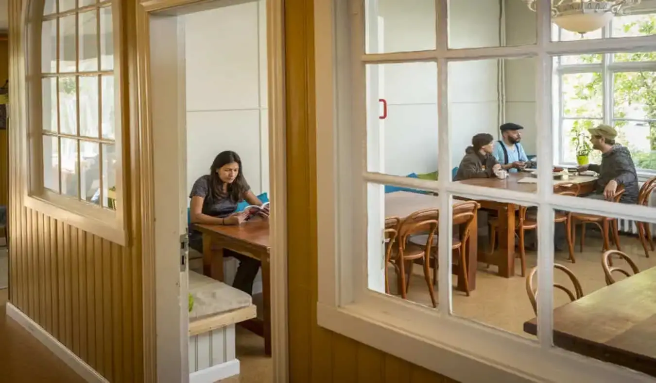 mennesker, der sidder ved langbord i Hafaldan hostels fællesrum