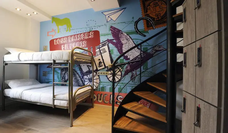 Zimmer mit Etagenbett, hell dekorierter Wand und einer Wendeltreppe im 3 Ducks Hostel in Paris