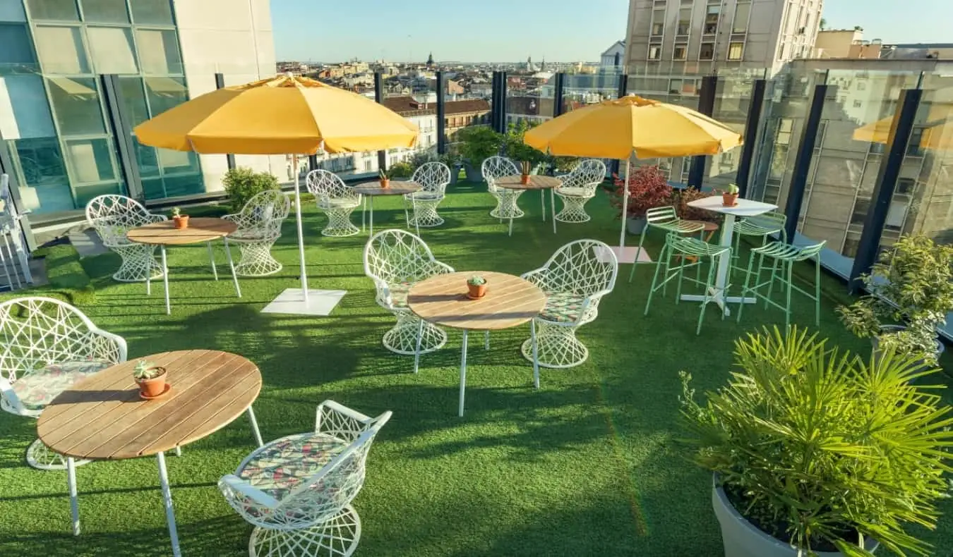 Takterrassen på Generator hostel med mange runde bord og stoler, med utsikt over hustakene i Madrid, Spania.