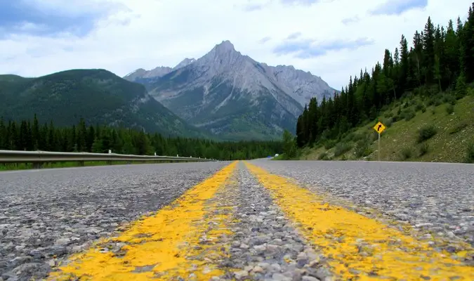 Linee stradali gialle che vanno in direzione di una montagna lontana