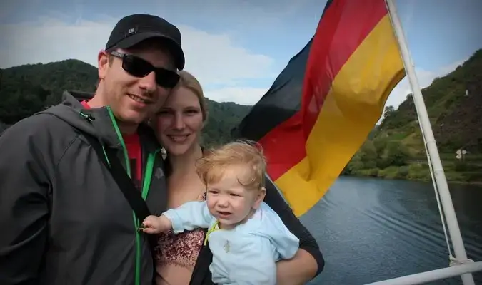 Família viajando de três pessoas posando com uma bandeira alemã