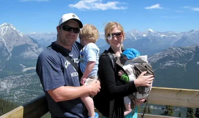 Famiglia di quattro persone in viaggio di fronte alla catena montuosa innevata