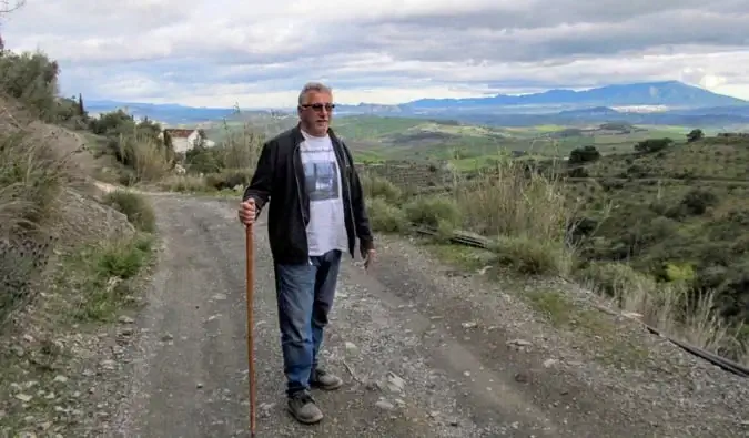 Un viajero jubilado caminando por una carretera vacía en Europa