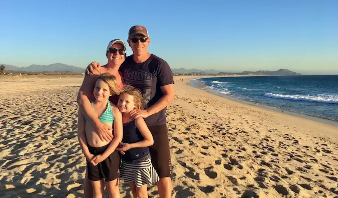 Amanda en haar reizende familie poseren op het strand