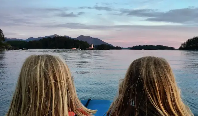 Twee jonge reizende kinderen poseren in de buurt van water bij zonsondergang