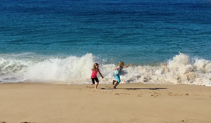 Twee jonge reizende kinderen die plezier hebben op het strand