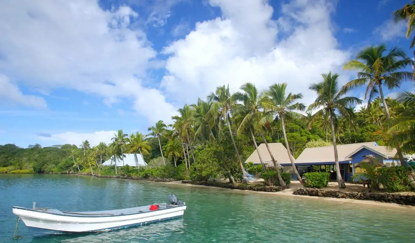 เรือในน้ำทะเลสีฟ้าใสนอกชายฝั่งของเกาะในฟิจิ