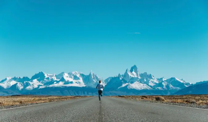 一个独自旅行者沿着一条铺好的路跑向雪山