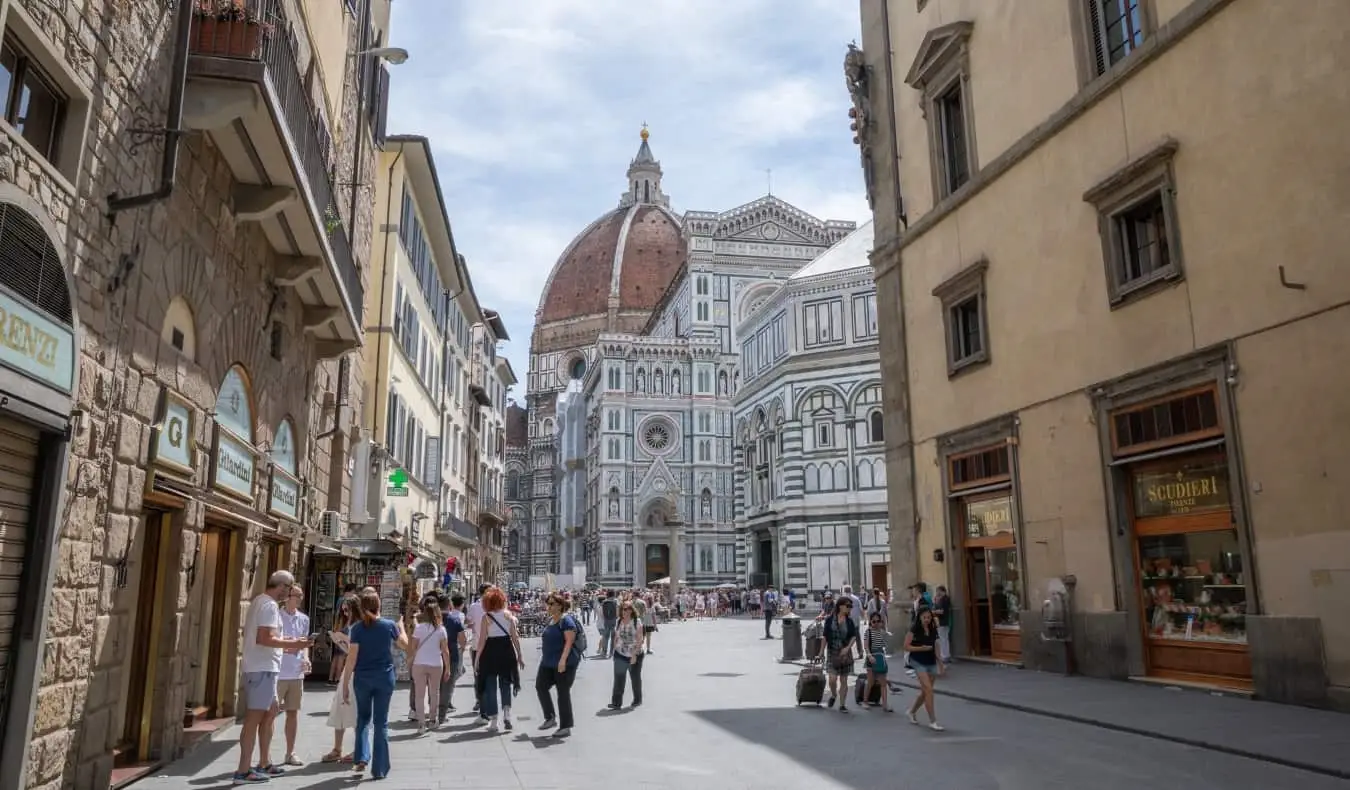 Menschen tummeln sich auf der Straße mit dem berühmten Dom im Hintergrund in Florenz, Italien