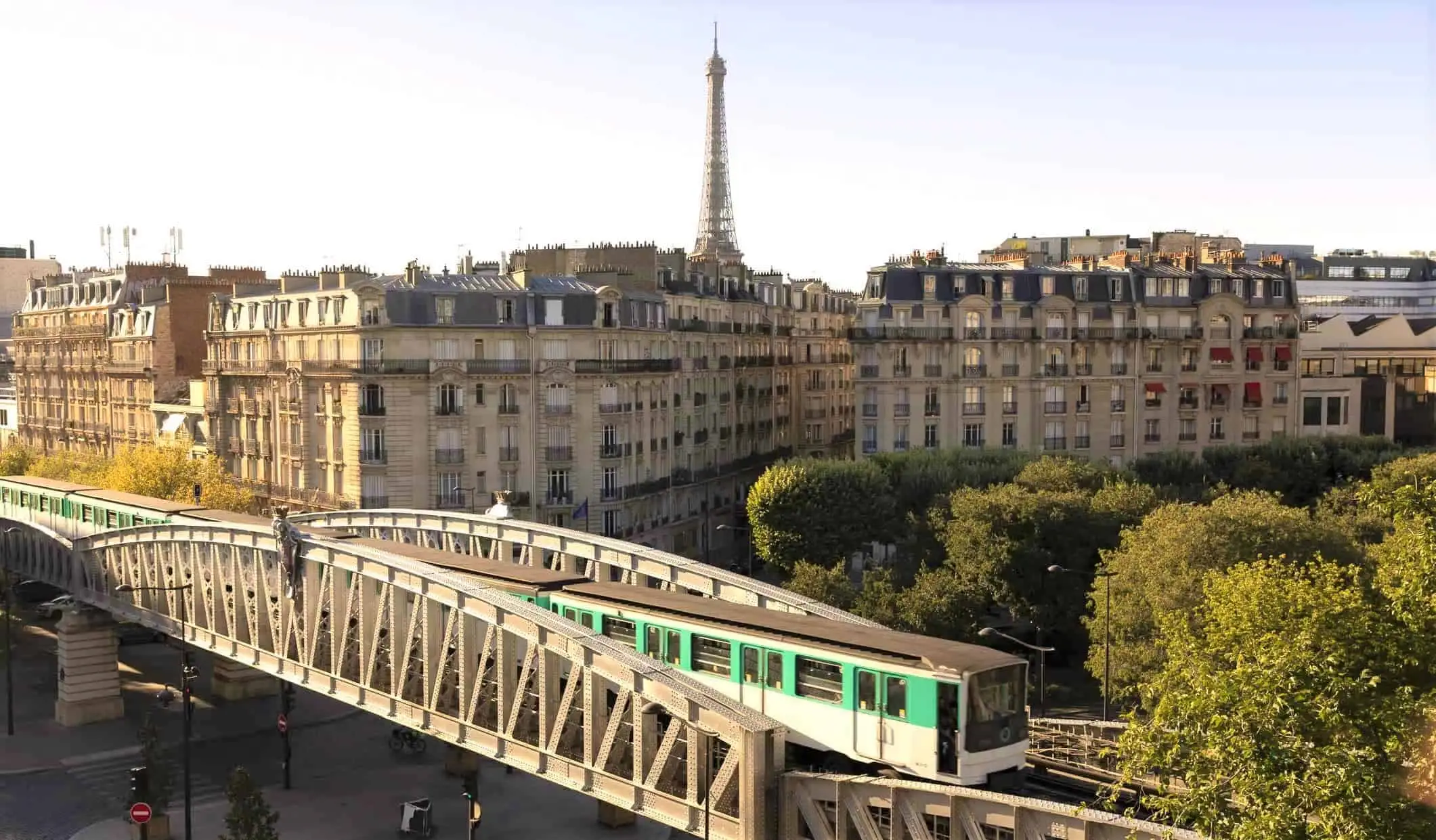 Et tog krysser en bro i forgrunnen med Eiffeltårnet i bakgrunnen i Paris, Frankrike