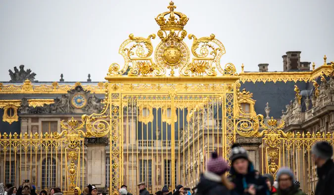 De ekstravagante portene til slottet i Versailles i Frankrike omgitt av besøkende