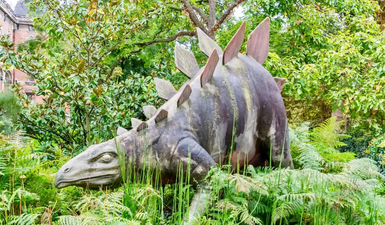 Eine Dinosaurierstatue im hohen Gras in Paris, Frankreich