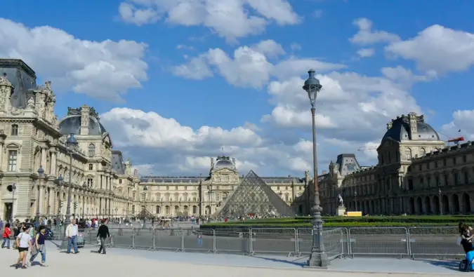 Turistas explorando o exterior do Louvre em Paris, França