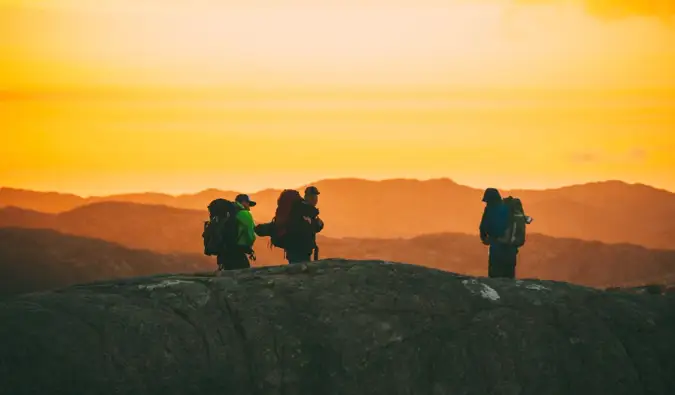 sekelompok pelancong hiking saat matahari terbenam di Norwegia