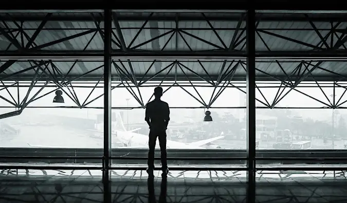 Una foto en blanc i negre d'un viatger sol dret en un aeroport