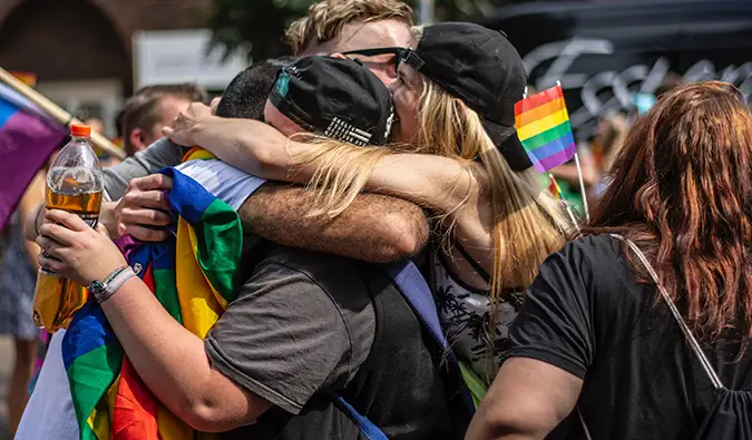 mujeres abrazándose en medio de un desfile del orgullo gay