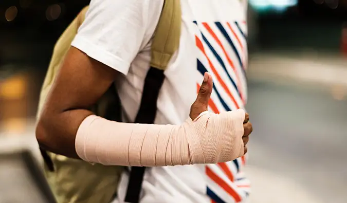 een man met gips draagt ​​zijn duimen omhoog