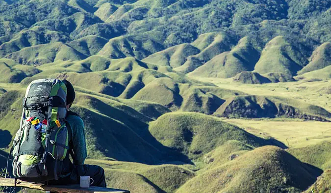 Isang nag-iisang hiker na nakaupo sa isang tagaytay na tinatamasa ang magandang tanawin sa tanawin sa harapan niya