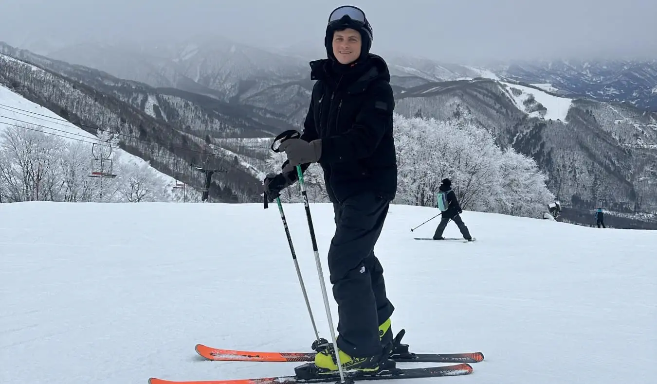 Nomadski Matt stoji na smučeh na zasneženi gori na Japonskem