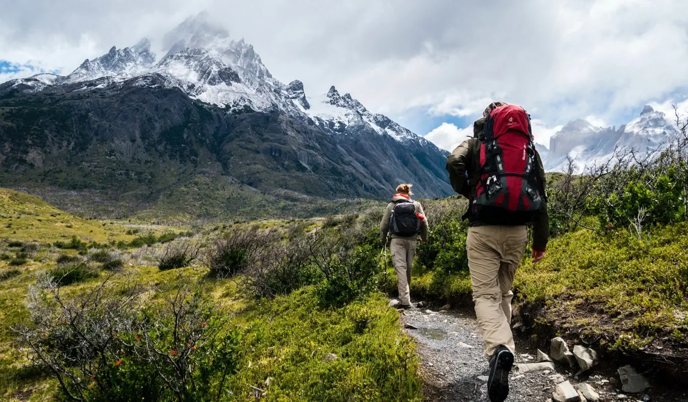 Un excursionista caminant per un sender cap a muntanyes nevades