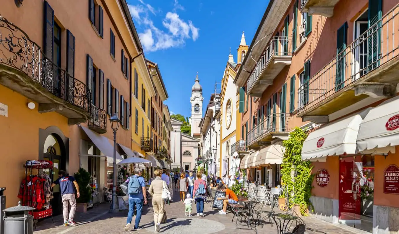 Žmonės, tyrinėjantys siaurą gatvelę spalvingame gražios, saulėtos Italijos mieste