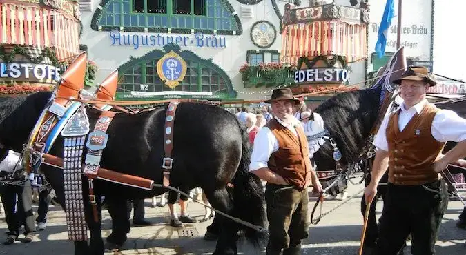 Oktoberfest'te geleneksel Bavyera kıyafetleri giyen ve atlarımı ayakta tutan erkekler